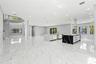 Open-concept living space featuring large-format tile flooring, dual kitchen islands with contrasting waterfall-edge stone surfaces, recessed ceiling 