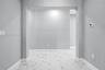 Large-format tile flooring featuring high-contrast veining, neutral grey wall paint, and a wide architectural archway