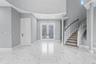 Foyer featuring large-format veined tile flooring, a curved staircase with white spindles, high ceilings with recessed lighting, and double-entry door