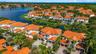 Aerial perspective featuring multi-story residences with terracotta-style tile roofing, paved driveways, multi-car garages, and mature palm landscapin