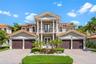 Neoclassical exterior featuring a symmetrical facade, two-story columns, second-level balcony with metal railing, clay tile roof, and a central tiered