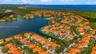 Aerial perspective of a multi-story residence with a tile roof situated in a waterfront community featuring extensive lake frontage and mature palm tr