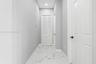 Hallway featuring polished tile flooring with a veined pattern, recessed ceiling lighting, and crisp white interior doors with matte black hardware