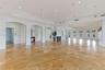 Expansive interior featuring large-format stone flooring, recessed ceiling lighting, multiple architectural archways, and oversized windows