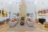 Great room featuring soaring double-height ceilings, a floor-to-ceiling stone-clad fireplace, natural stone flooring, and clerestory windows