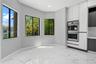 Large-format tile flooring with veining, bay windows, built-in stainless steel double wall oven, and sleek floor-to-ceiling cabinetry
