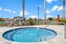 Circular spa featuring a stone-paver deck, built-in steps, a metal handrail, and a tile border