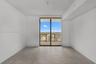 Neutral-toned tile flooring, floor-to-ceiling glass sliding door, and private balcony with metal railing
