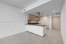Kitchen featuring wood-finish upper cabinetry, a stainless steel range hood, integrated refrigerator, stone-surface countertop, and ceramic tile floor
