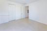 Neutral interior space featuring large-format tile flooring, a dual-panel closet with brushed nickel hardware, and a solid-core interior door