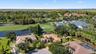 Aerial perspective of a residential property featuring tile roof construction, a screened-in lanai, and landscaped grounds situated on a golf course