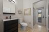 Bathroom featuring a vanity with dark-finish cabinetry, a rectangular vessel sink, and a matte black faucet, complemented by polished stone-finish flo