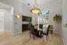 High-ceiling room featuring large arched window with plantation shutters, built-in dark wood cabinetry, polished light-tone tile flooring, and integra