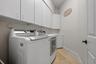 Laundry area featuring extensive upper cabinetry, base cabinet storage, and wood-finish flooring