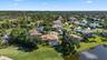 Aerial perspective of a property featuring a screened-in swimming pool, tile roof, and manicured landscaping, situated directly on a golf course fairw