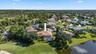 Aerial perspective of residence featuring a tile roof, screened-in swimming pool enclosure, and direct positioning on a golf course