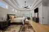 Tray ceiling with crown molding, wood-finish flooring, central ceiling fan, and multiple plantation-style shutters