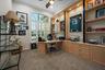 Built-in light-wood cabinetry with integrated shelving and recessed accent lighting, arched window with plantation shutters, and ceiling fan fixture