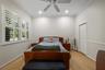 Room featuring wood-finish flooring, crown molding, chair rail trim, plantation shutters, and a ceiling fan