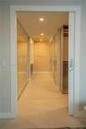 Hallway featuring tile flooring, textured wall covering, recessed lighting, and a wall of integrated wood-finish cabinetry with built-in shelving