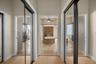 Hallway featuring dual floor-to-ceiling mirrored sliding closet doors, stone-tile flooring, and direct line-of-sight to an inset soaking tub with ston