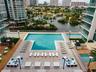 High-rise residential building featuring floor-to-ceiling glass windows, a rooftop pool, private balconies, and waterfront positioning