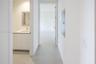 Hallway featuring neutral-toned flooring, white cabinetry with integrated countertop, a rectangular mirror, and a wall-mounted electrical panel