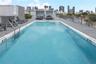 Rooftop swimming pool featuring gray composite decking, integrated metal railings, and built-in steps