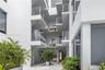 Multi-story architectural exterior featuring a white stucco facade, tiered balconies with horizontal metal railings, floor-to-ceiling glass windows, a