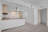 Kitchen featuring flat-panel light wood cabinetry, integrated appliances, stainless steel range hood, breakfast bar, and tile flooring