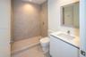 Bathroom featuring a walk-in shower with large-format wall tile, a white vanity with an integrated sink, a rectangular framed mirror, and chrome plumb