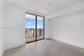 Floor-to-ceiling glass sliding door, balcony with metal railing, and neutral tile flooring