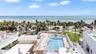 Rooftop swimming pool featuring glass panel perimeter fencing, masonry hardscaping, and an expansive ocean backdrop