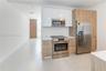 Kitchen featuring two-tone cabinetry with gloss white upper units, wood-finish lower cabinetry, integrated stainless steel appliances, solid-surface c
