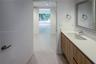 Floating wood-finish vanity with an integrated basin, smooth countertop, chrome faucet, and rectangular mirror