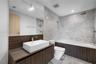 Contemporary bathroom featuring a floating wood-finish vanity with a rectangular white vessel sink, stone-look countertop, and chrome wall-mounted fau