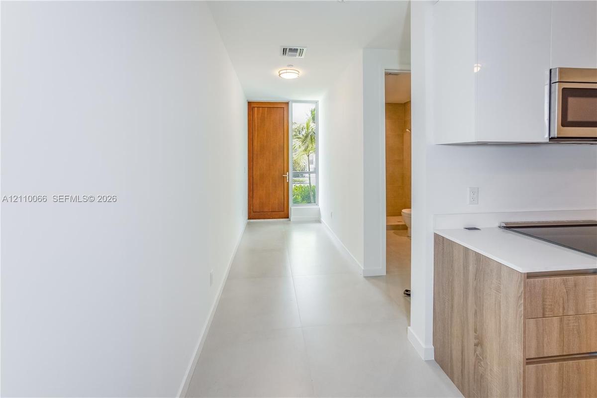 Entryway featuring a solid wood door, large-format tile flooring, and clean-lined cabinetry with a matte finish