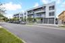 Modern multi-story residential building featuring a smooth stucco facade, glass-paneled balconies, rooftop terraces, spiral staircase architectural el