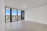 Open interior space featuring light-toned tile flooring, floor-to-ceiling windows, and a tiled private balcony with glass railing