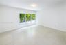 Interior space featuring large-format tile flooring, a triple-pane window system, flush-mount circular lighting, and smooth-finish white walls