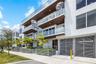 Modern multi-level exterior featuring white stucco cladding, integrated wood-finish balcony ceilings, glass railings, metal spiral staircases, and lou