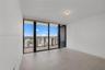 Floor-to-ceiling glass windows, neutral tile flooring, and a glass-paneled balcony with outdoor tiling