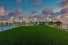 Rooftop terrace featuring artificial turf and a metal horizontal-bar railing, set against a cityscape backdrop