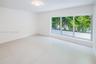 Neutral-toned tile flooring, large three-pane picture window, recessed ceiling lighting, and exterior greenery