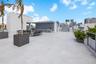 Expansive rooftop terrace featuring concrete flooring, a built-in outdoor kitchen with patterned tile backsplash, metal railings, and integrated plant