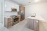 Kitchen featuring white gloss upper cabinetry, wood-finish lower cabinetry, a stainless steel appliance suite, stone-surface countertops, and a centra