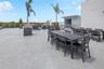 Expansive rooftop terrace featuring large-format concrete tiling, horizontal metal perimeter railings, and integrated structural planters