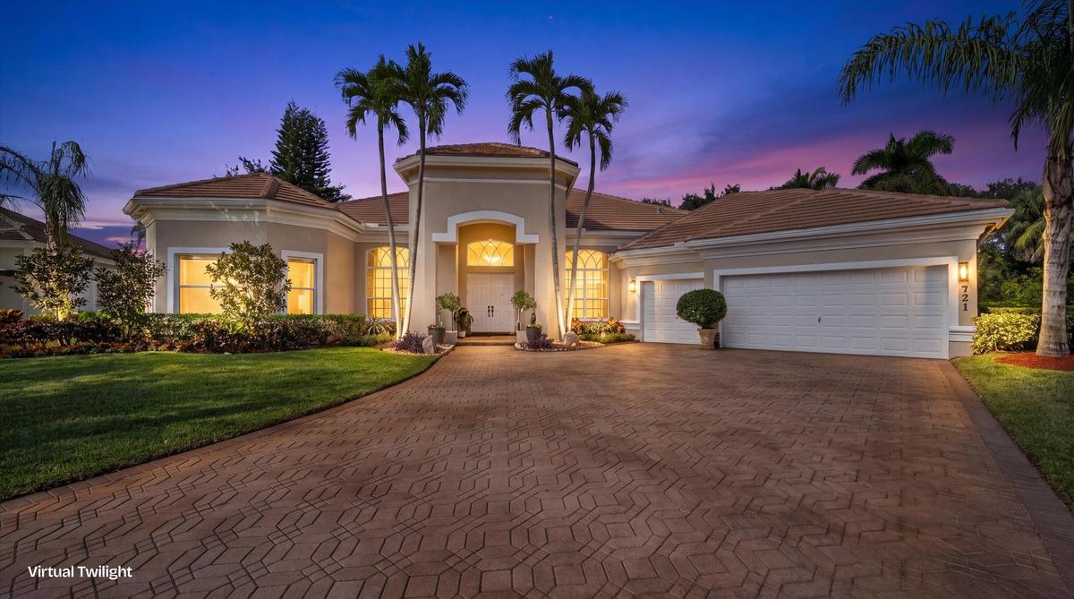 Stucco exterior featuring a tiled roof, arched entryway, paved driveway, and established palm trees