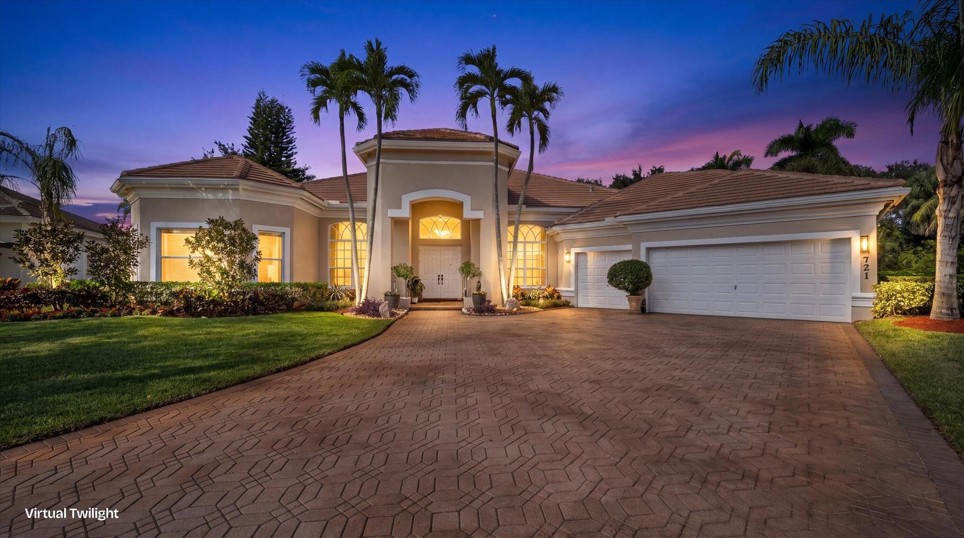 Stucco exterior featuring a tiled roof, arched entryway, paved driveway, and established palm trees