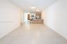 Kitchen featuring white high-gloss upper cabinetry, wood-finish base cabinetry, stainless steel appliances, and a central island with a countertop